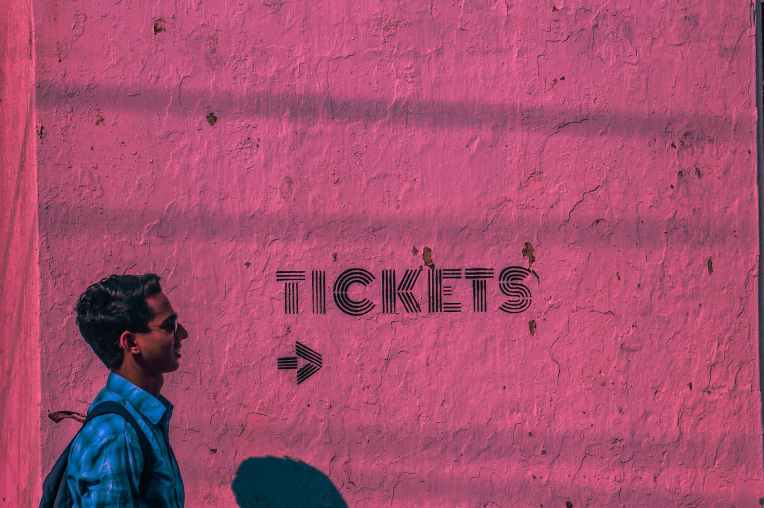 man wearing blue sports shirt and backpack passing through pink wall